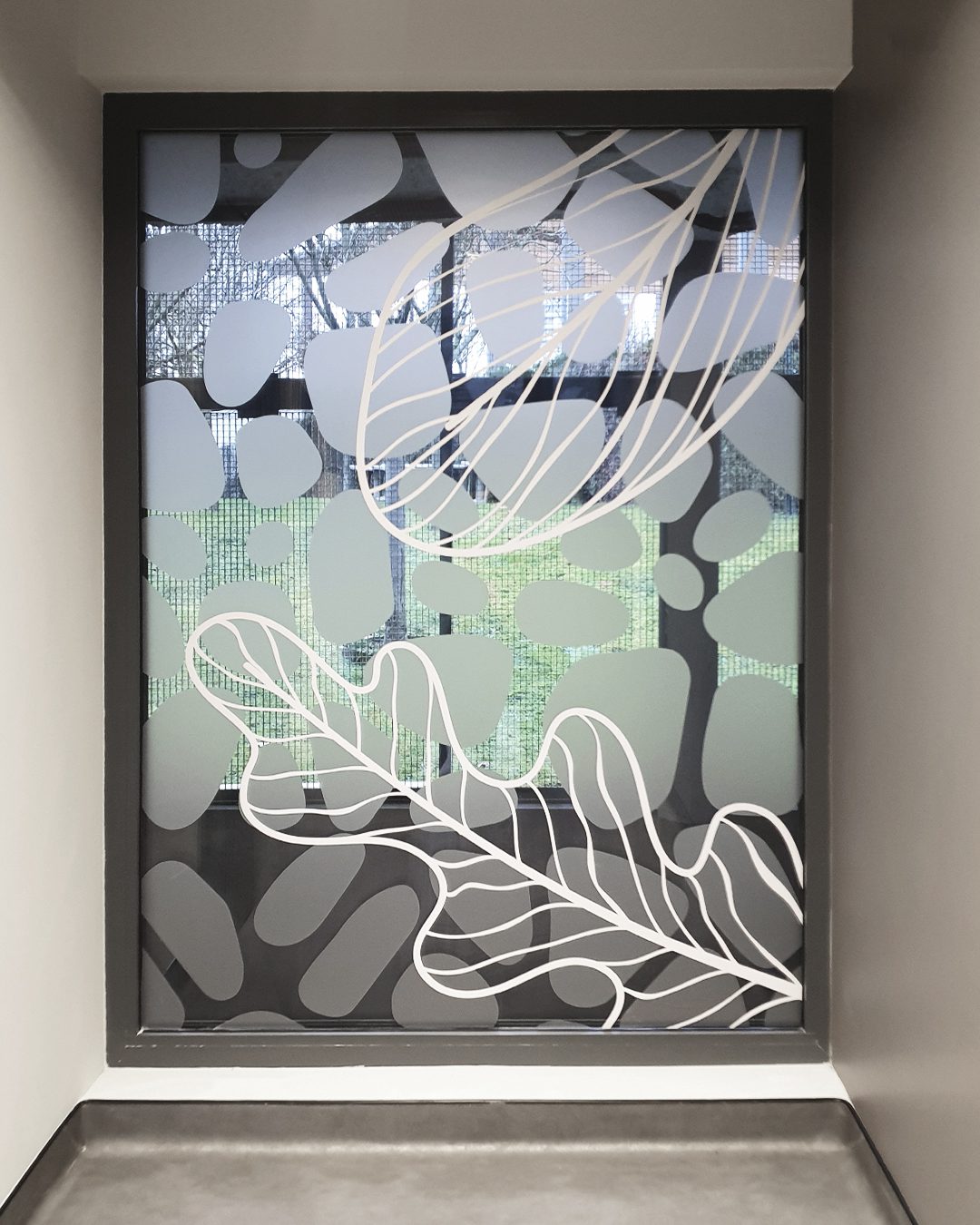 Vitre intérieure ornée de formes ovales et de grands motifs de feuilles blanches sur fond translucide