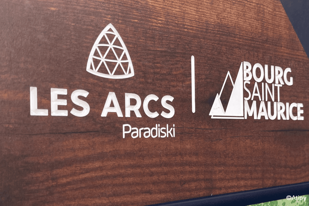 Logos Les Arcs Paradiski et Bourg Saint Maurice en blanc sur un panneau brun aspect bois