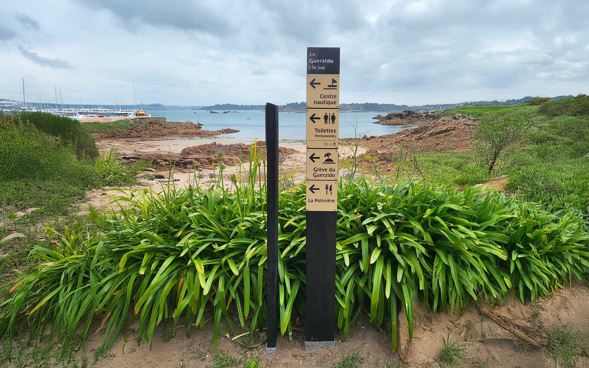 Panneau directionnel touristique sur le littoral indiquant centre nautique, toilettes et grève du Guerzido