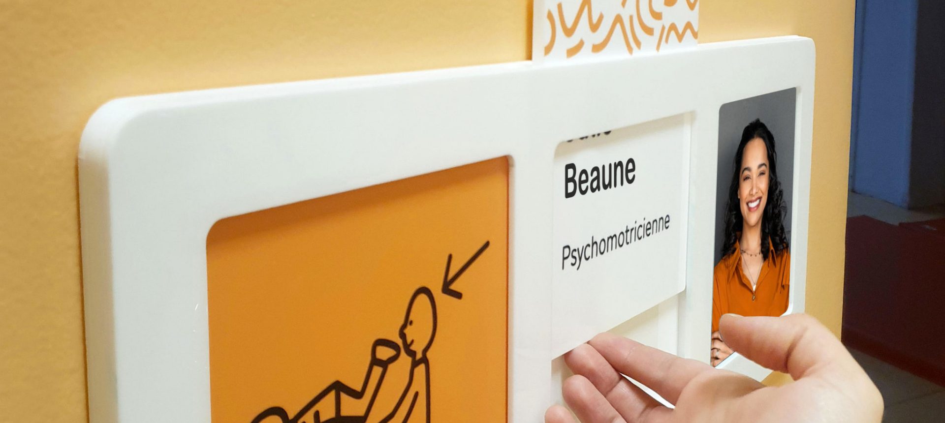 Plaque de porte avec pictogramme orange, nom Beaune, fonction psychomotricienne et portrait tactile coulissant