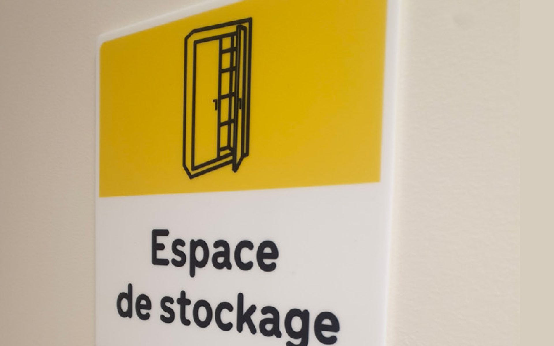 Panneau mural jaune et blanc avec pictogramme de porte ouverte et texte « Espace de stockage