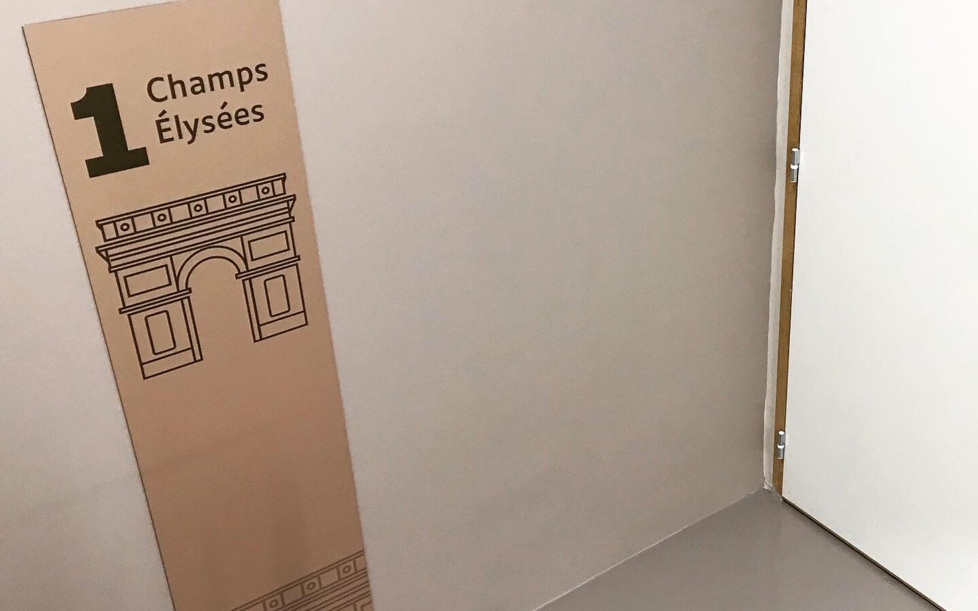 Panneau signalétique incliné avec le numéro 1, texte Champs Élysées et dessin de l’Arc de Triomphe