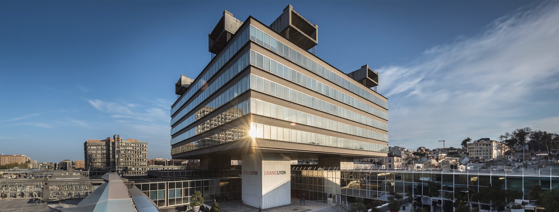 Bâtiment Grand Lyon aux façades vitrées avec le nom GRANDLYON visible sur deux piliers à l’entrée