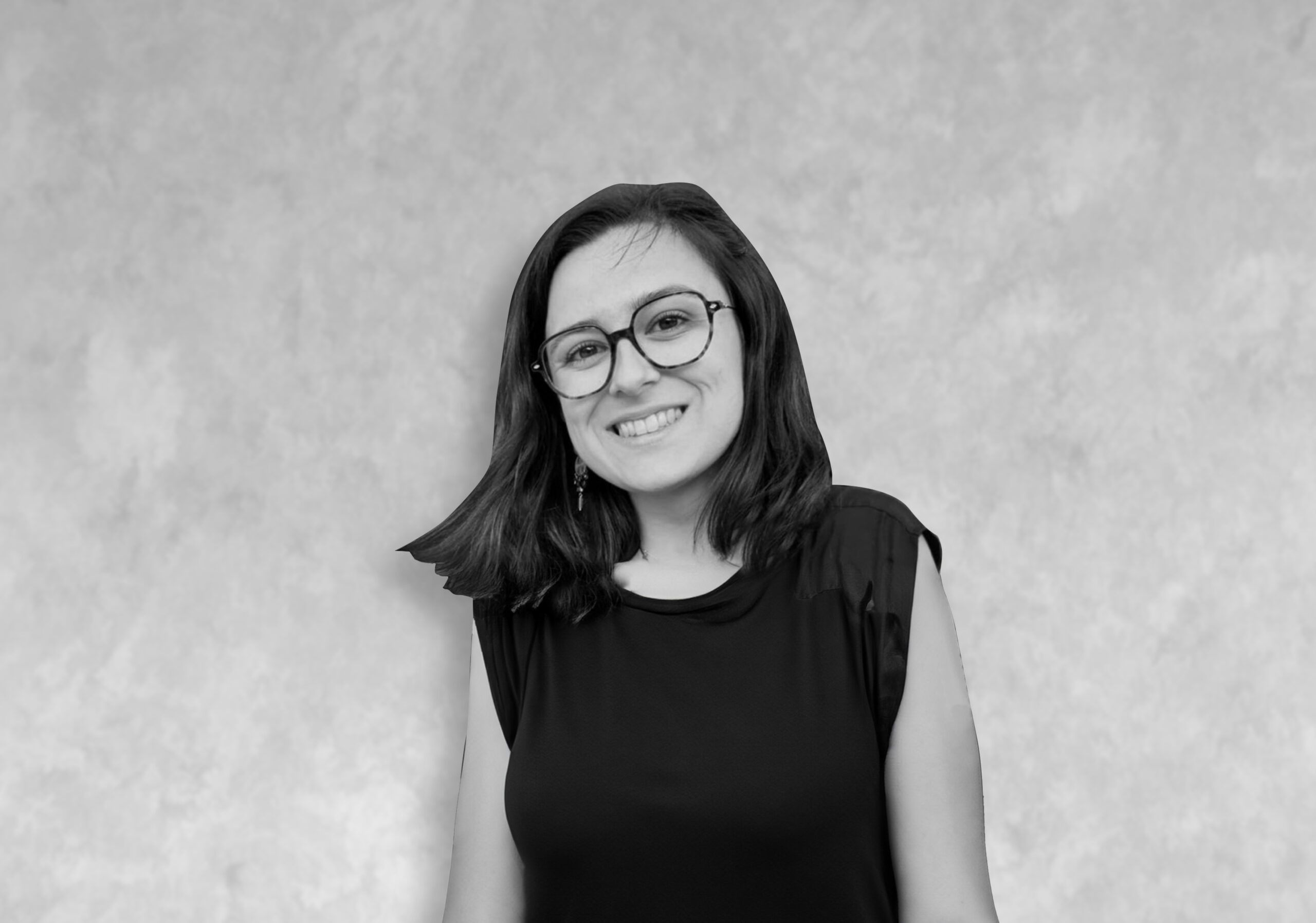 lea Portrait d’une femme aux cheveux mi-longs foncés, vêtue d’un haut noir, devant un mur clair texturé