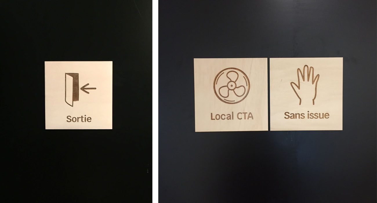 Plaques signalétiques en bois sur portes sombres avec pictogrammes et textes Sortie, Local CTA et Sans issue