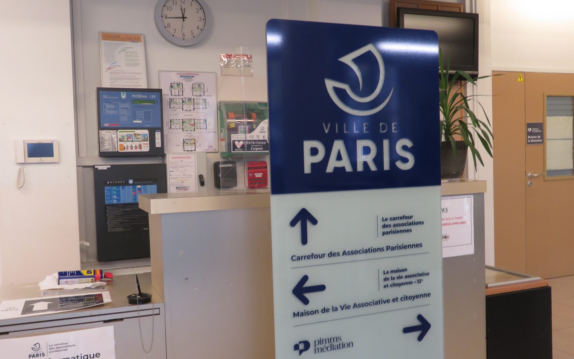 Totem directionnel Ville de Paris dans un hall d’accueil avec flèches vers associations et médiation